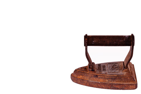 Vintage things. Close up of old style rusty iron isolated on white background. Antique iron heated on fire. Vintage cast iron or steel iron. Old iron isolated on white background.のeditorial素材