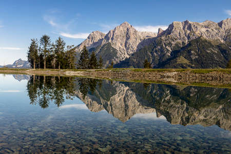 Prinzensee lake in Austria in the region of Hochkoenig Salzburg. The mountains in the background reflect in the mirro surface of the lake. A car is parked in the left side of the picture.の写真素材