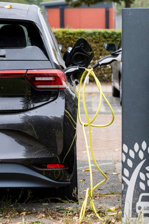Charging an electric car with a cable in the streetの写真素材