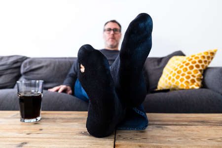 Man with a hole in his sock sitting on the couch