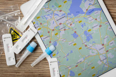 Covid home testing kits laying on a table next to a map of Amsterdam Netherlands
