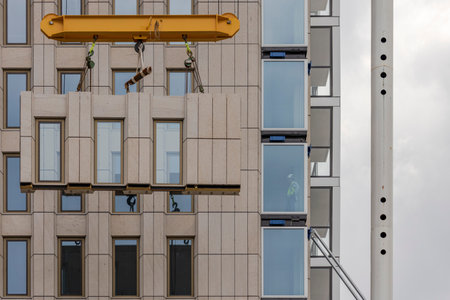 Rotterdam, Netherlands - 2020-6-15: Construction of a skyscraper building hoisting prefab elements while a construction worker is supervisingのeditorial素材