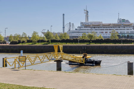 Rotterdam, the Netherlands - 2022-04-21: People boarding a water taxi near historic cruise ship SS Rotterdam that is now a hotelのeditorial素材