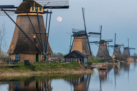 Windmills of Kinderdijk Alblasserdam UNESCO site in the Netherlands under a rising full moonのeditorial素材