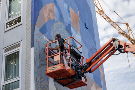 rotterdam, the Netherlands - 2023-09-27: Artist painting a mural using a cherry-picker