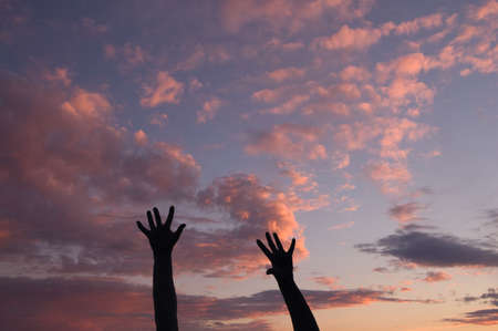 Silhouettes of two women's hands at sunsetの写真素材
