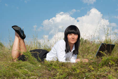 Young attractive lady on the meadow relaxing and using  laptopの写真素材