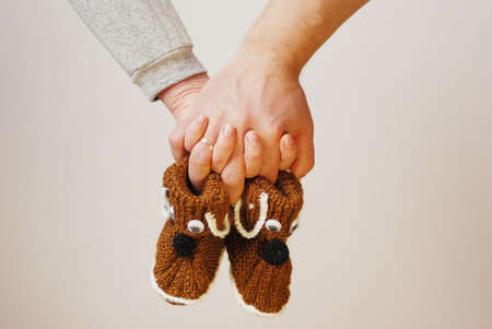 Happy father and mother hold in their hands baby shoes of their future first childの写真素材