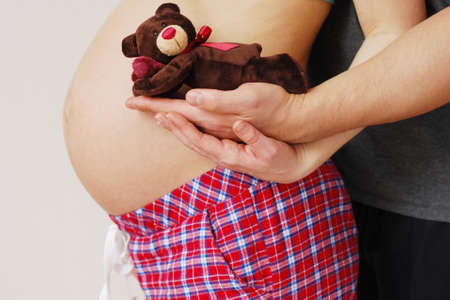 Happy young parents show atoy of their future baby on background of big belly pregnant motherの写真素材