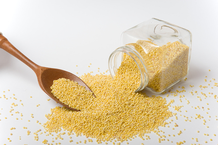 Hulled Millet in a glass jar and on a wooden spoonの写真素材