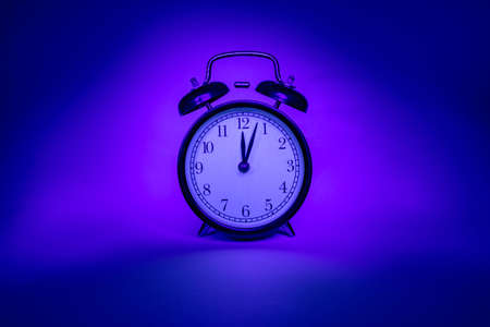 Alarm clock on a pink-blue background. Isolated object.の写真素材