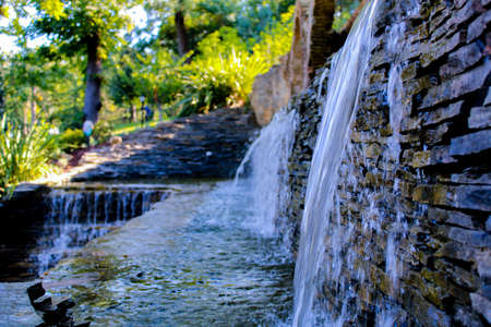 An artificial waterfall in Emirgan Park in Ä°stanbul. In the background, the sun is shining on the trees and the grass.の写真素材
