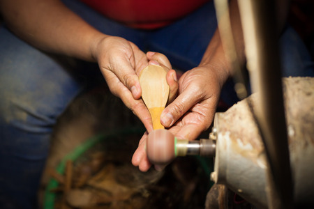 Artisan hands at work, carving wood into spoonsの写真素材