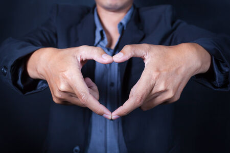 Business man make heart shape with his handの写真素材
