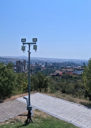 a surveillance camera on a pole on the street. Street lighting