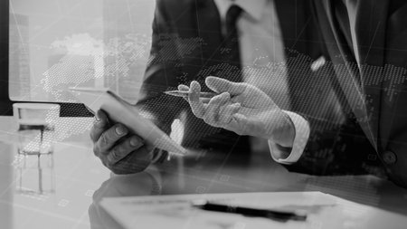 business documents on office table with smart phone and digital tablet and graph business diagram and man working in the backgroundの写真素材