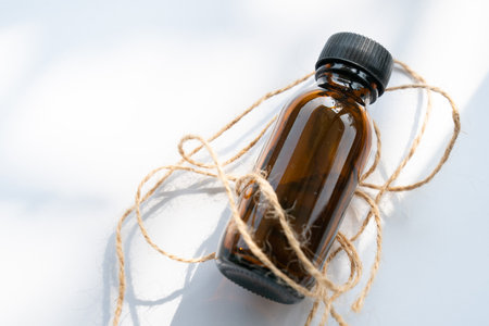 Essential oil in a glass bottle with a rope on a white background