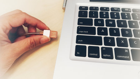 Hand holding USB flash drive on laptop keyboard, technology and internet concept