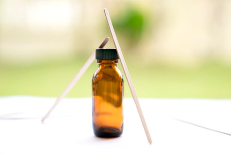 Essential oil in a glass bottle on a white table with wooden sticksの写真素材