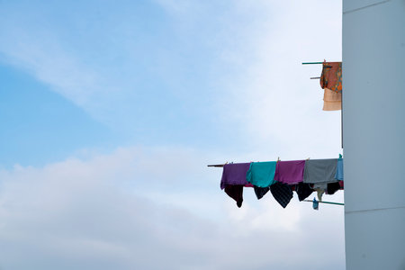 Clothes hanging on a clothesline against blue sky with clouds.の写真素材