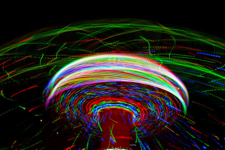 Carnival amusement park ride with swings. Spinning fair ride at night with bright purple, red, green and yellow lights.の写真素材