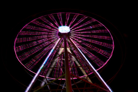 Carnival amusement park ride with swings. Spinning fair ride at night with bright purple, red, green and yellow lights.の写真素材