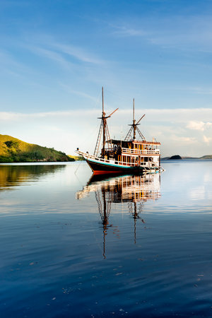 Sail boat reflection on the sea with mountain in the backgroundの写真素材
