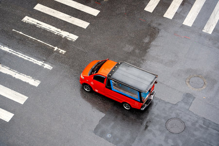 Aerial view of a red car crossing on a crosswalk in the cityの写真素材