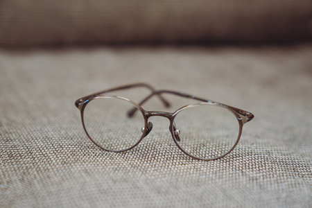 Eyeglasses on a brown fabric background. Selective focus.