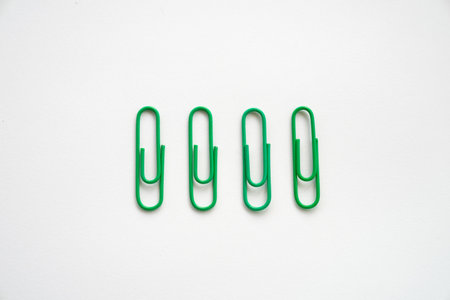 Green Coloured paper clips close-up on a white background