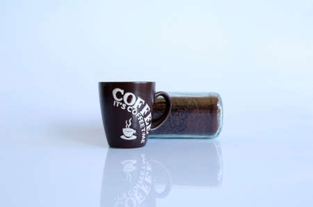 A black coffee storage tin next to a black and white mugの写真素材