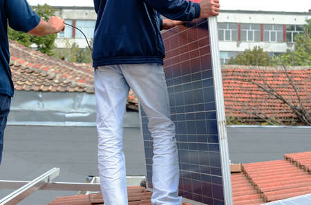 Worker and Solar panels on a house roof