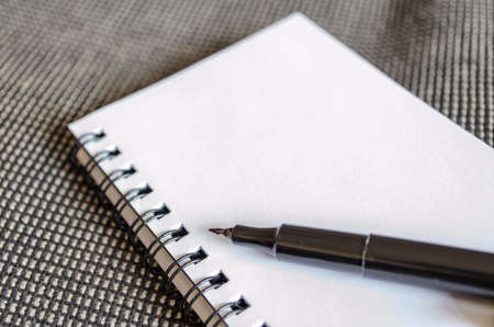 White notepad and ink pen on the wooden deskの写真素材