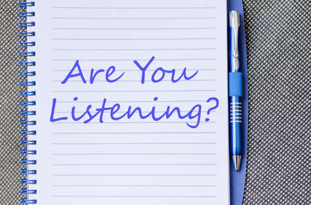 Notepad and pen on wooden background and are you listening? text conceptの写真素材
