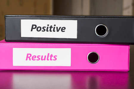 Bright office folders over dark background and positive results text conceptの写真素材