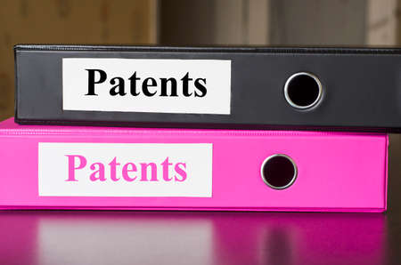Bright office folders over dark background and patents text conceptの写真素材