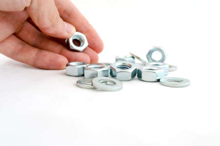 Several metal screw washers and nuts in human hand isolated on white background.