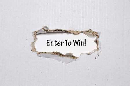 The word enter to win appearing behind torn paperの写真素材