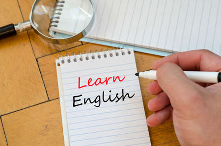 Learn english text on White notepad and human hand on the wooden backgroundの写真素材