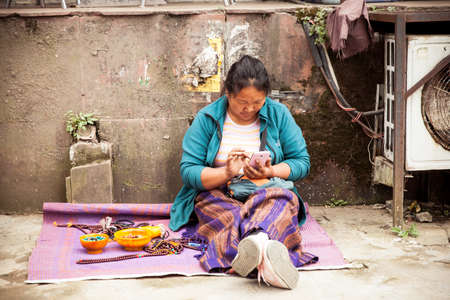Dharamsala, India - 28 September, 2014: Tibetian woman with a smartphone at the street market, Dharamsala, India.のeditorial素材