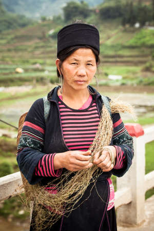 Sapa, Lao Cai, Vietnam -  5 May 2014: The portrait of tribal Hmong woman in national clothes  standing on the road near rice fields with hay in the hands on 05 May 2014 in Sapa, Northern Vietnam.のeditorial素材