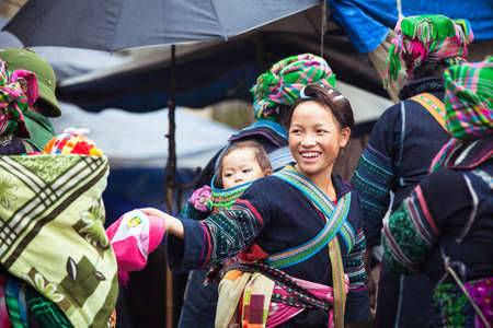Sapa, Lao Cai, Vietnam - 6 May 2014: Hmong tribal woman with baby in national clothes on the local market, Sapa, Northern Vietnam on 06 May 2014.のeditorial素材