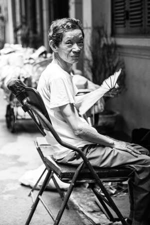 Hanoi, Vietnam - April 25, 2014: Vietnamese senior man restnig on his chair with fan on the street of Hanoi, Vietnam on April 25, 2014.のeditorial素材