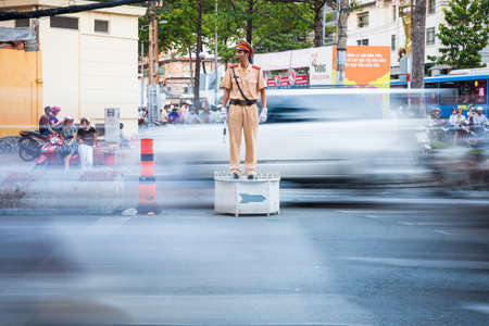 Ho Chi Minh City, Vietnam - November 19, 2015: Vietnamese pointsman regulate traffic at the busy crossroad on November 19, 2015 in Ho Chi Minh City, Vietnam.のeditorial素材