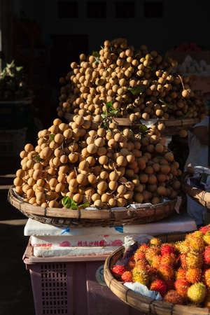 Baskets full of tropical longan fruit under morning light at the street market, Vietnam.の写真素材