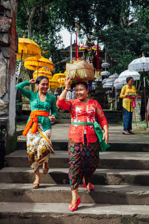 Ubud, Indonesia - March 02, 2016: Balinese women in traditional clothes  carrying ceremonial box with offerings on the head during Balinese New Year or Nyepi Day celebrations on March 02, 2016 in Ubud, Bali.のeditorial素材