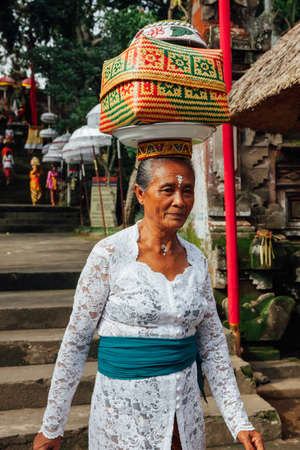 Ubud, Indonesia - March 02, 2016: Balinese woman in traditional clothes  carrying ceremonial box with offerings on her head during Balinese New Year or Nyepi Day celebrations on March 02, 2016 in Ubud, Bali.のeditorial素材