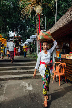 Ubud, Indonesia - March 02, 2016: Balinese woman in traditional clothes  carrying ceremonial box with offerings on her head during Balinese New Year or Nyepi Day celebrations on March 02, 2016 in Ubud, Bali.のeditorial素材