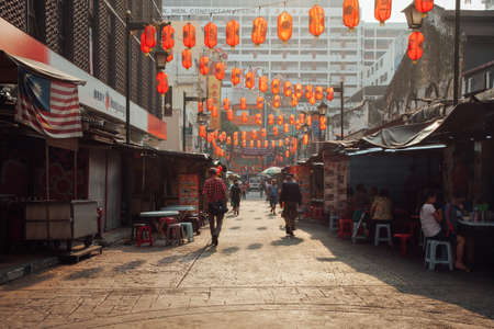 Kuala Lumpur, Malaysia - March 17, 2016: People walking through Petaling Street while other eating at the street stalls in Chinatown during the morning hour, Kuala Lumpur, Malaysia on March 17, 2016.のeditorial素材