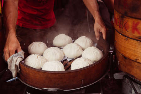 Young man cooking chinese traditional steamed buns at the street food stall in Chinatown, Kuala Lumpur, Malaysia on March 17, 2016.のeditorial素材